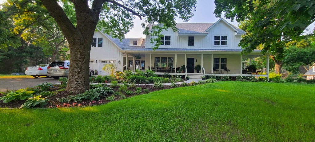 After — finished farmhouse with NanaWall glass walls and wrap-around porch