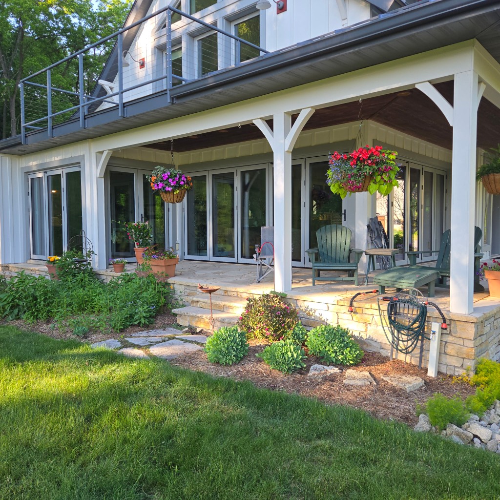 Modern farmhouse with NanaWall folding glass doors opening to a stone patio